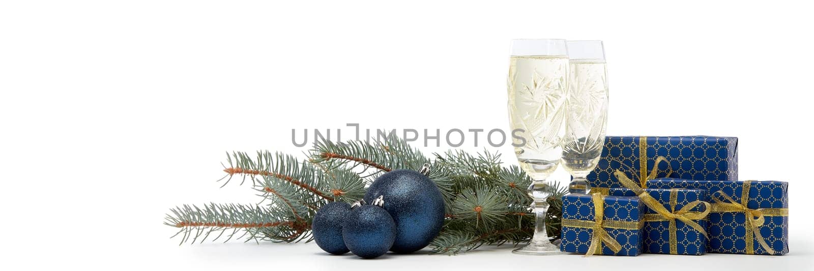 Still life with two champagne flutes, gift boxes and Christmas decoration with fir tree branch isolated on white background with copy space. Christmas and New Year shopping. Greeting card
