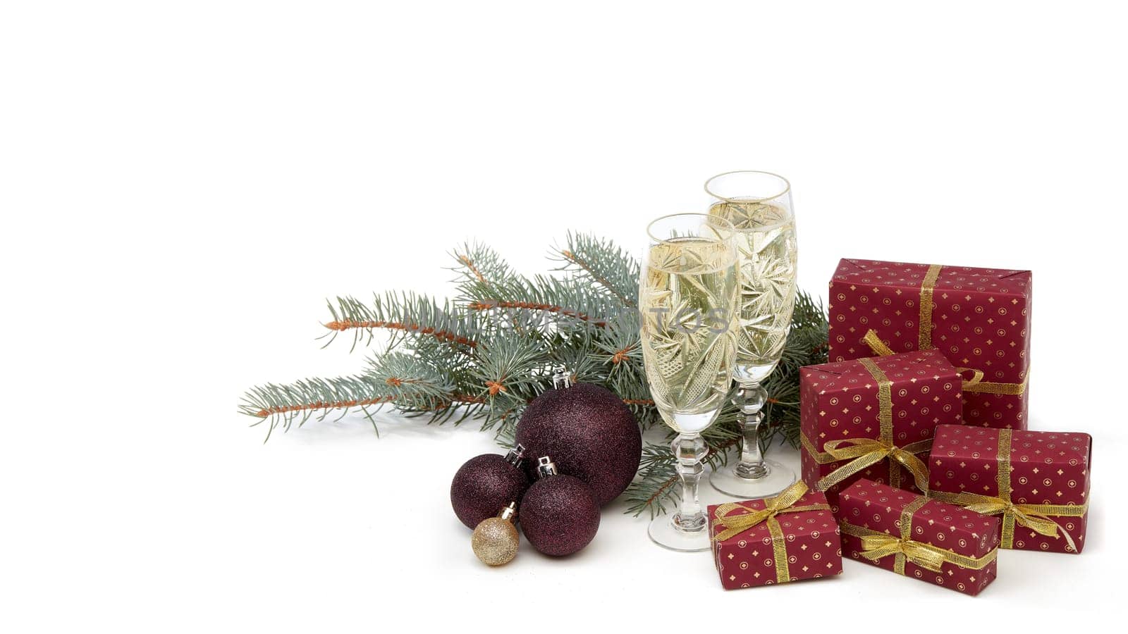 Still life with two champagne flutes, gift boxes and Christmas decoration with fir tree branch isolated on white background. Christmas and New Year shopping. Greeting card
