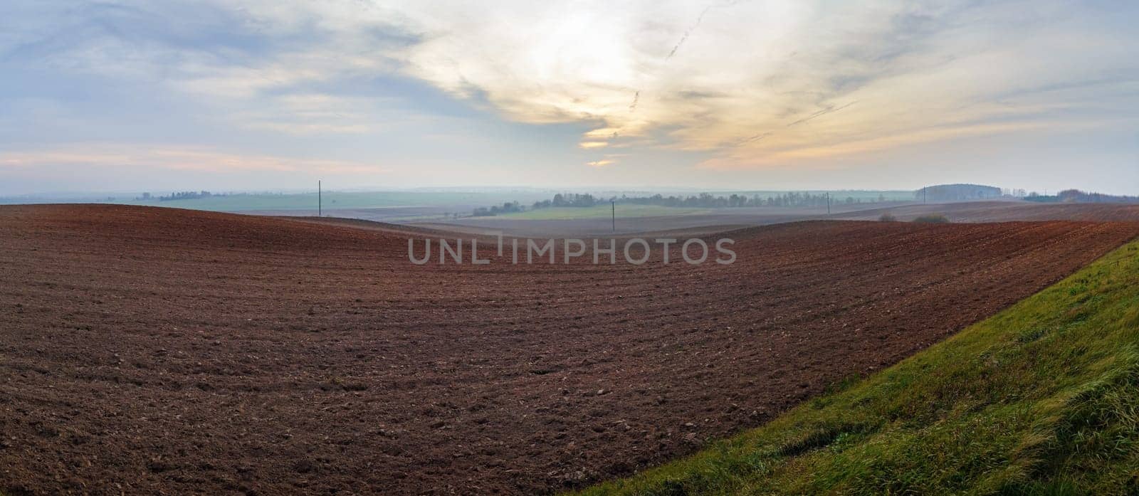 Panorama of arable land. Agricultural rural landscape. Evening in the countryside. Panoramic shot.