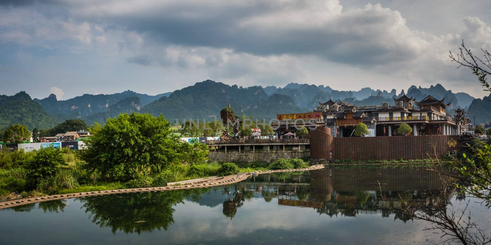 Wulingyuan, China - August 2019 : Riverside buildings with the stunningly beautiful rocky karst mountain formations behind as seen from the centre of  town, Hunan Province