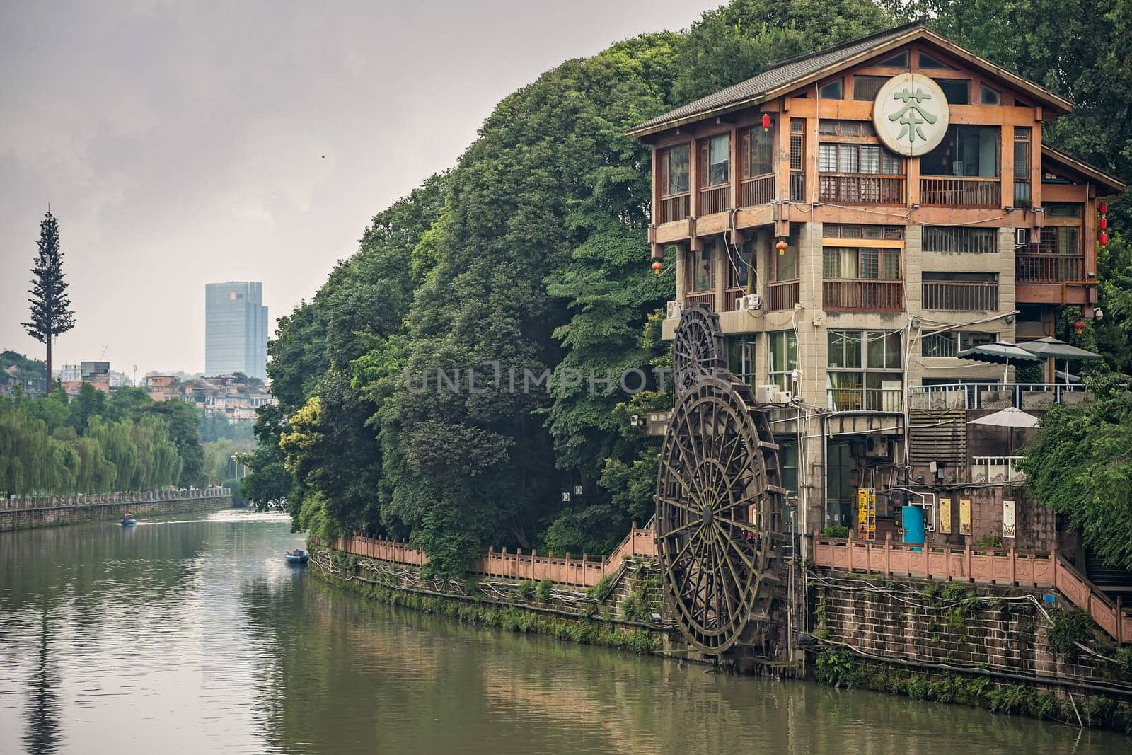 Chengdu, China -  July 2019 : Old mill building with big wooden wheel on the bank of Jin River flowing through Chengdu city, Sichuan Province