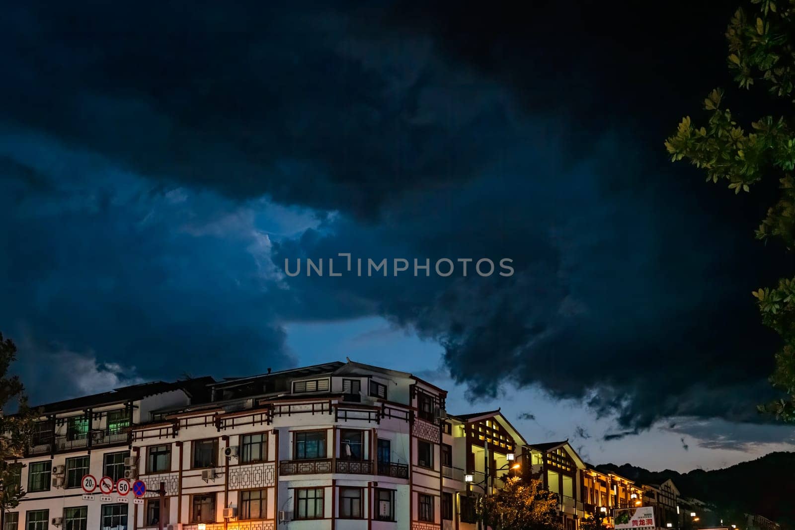 Wulingyuan, China - August 2019 : Residential buildings lit at night at a busy high street in Wulingyuan town at dusk