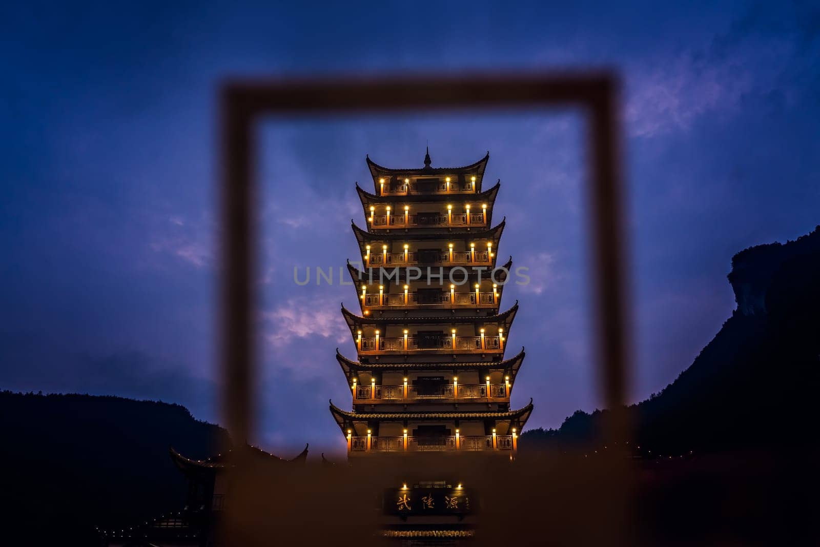 Wulingyuan, China - August 2019 : Framed  at dusk traditional chinese style wooden tower pagoda standing at the Wulingyuan entrance to the Zhangjiajie national park, Hunan Province