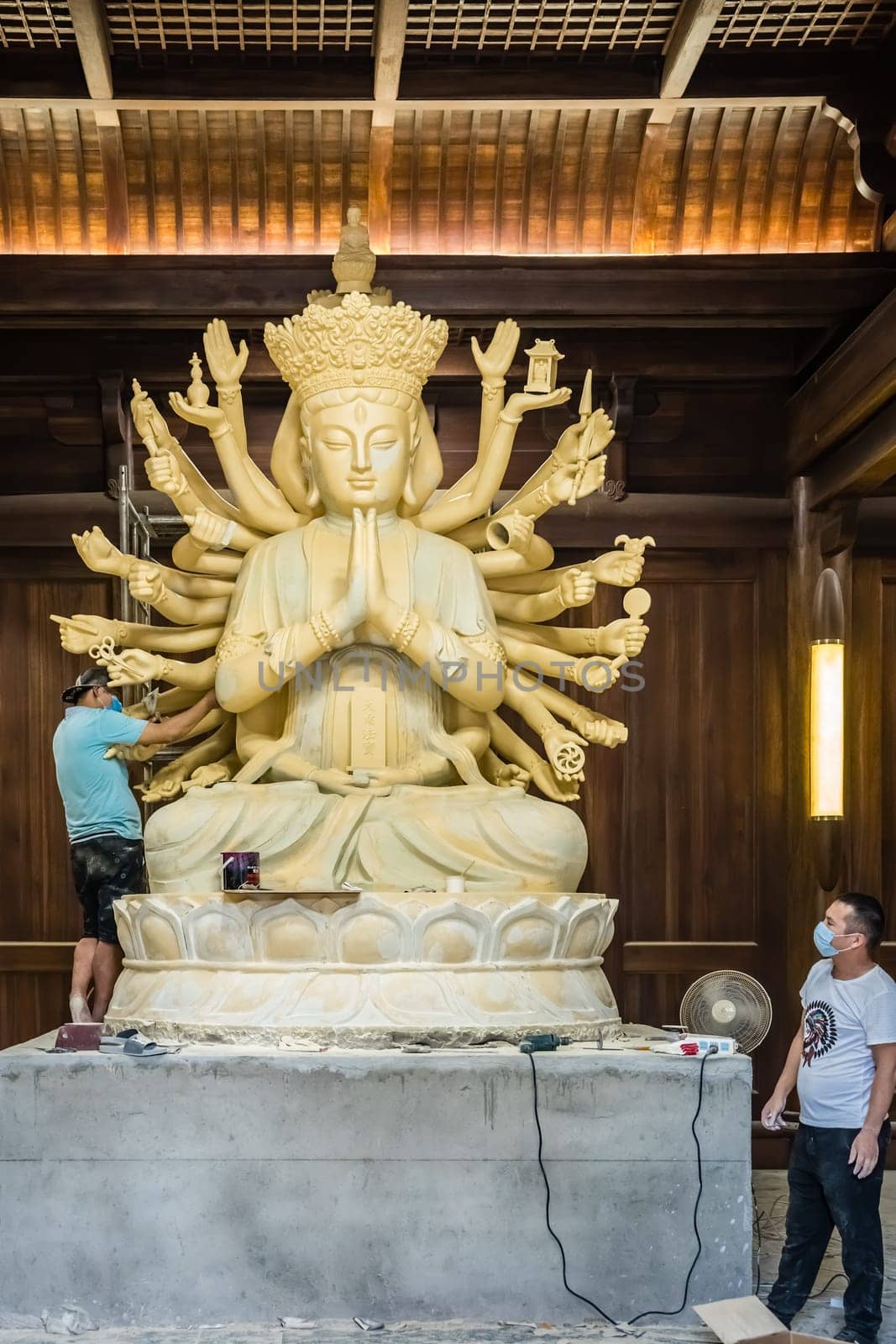 Chengdu, China -  July 2019 :  Male workers creating and restoring large sculpture of multi handed God Shiva in the courtyard of the Buddhist Wenshu Monastery