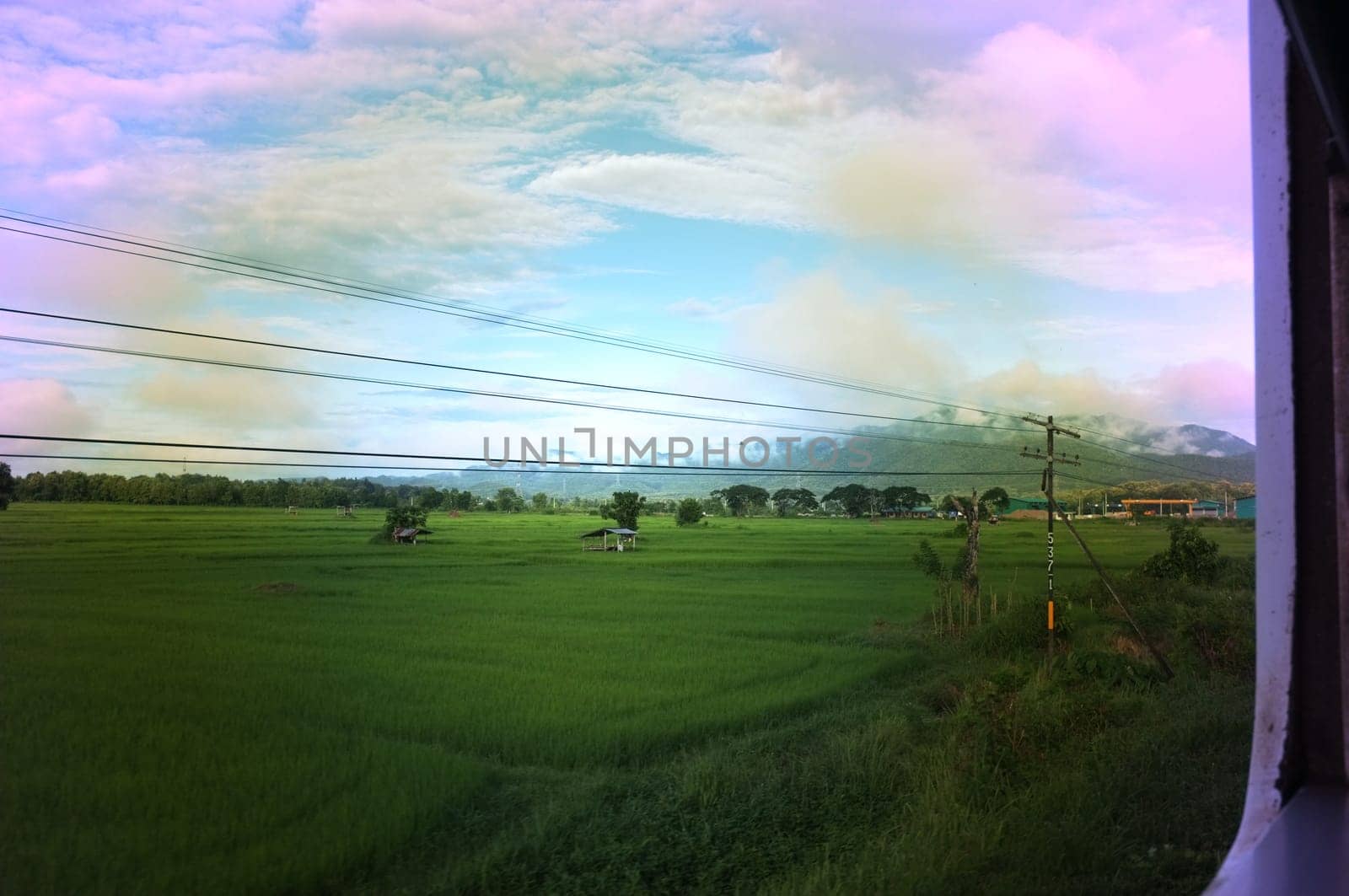 View from train window in motion of countryside and sky on sunny warm , in Thailand , Effect saturation