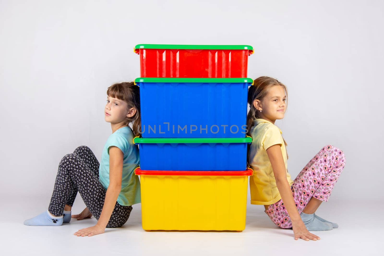 Two girls from different sides leaned their backs on plastic boxes