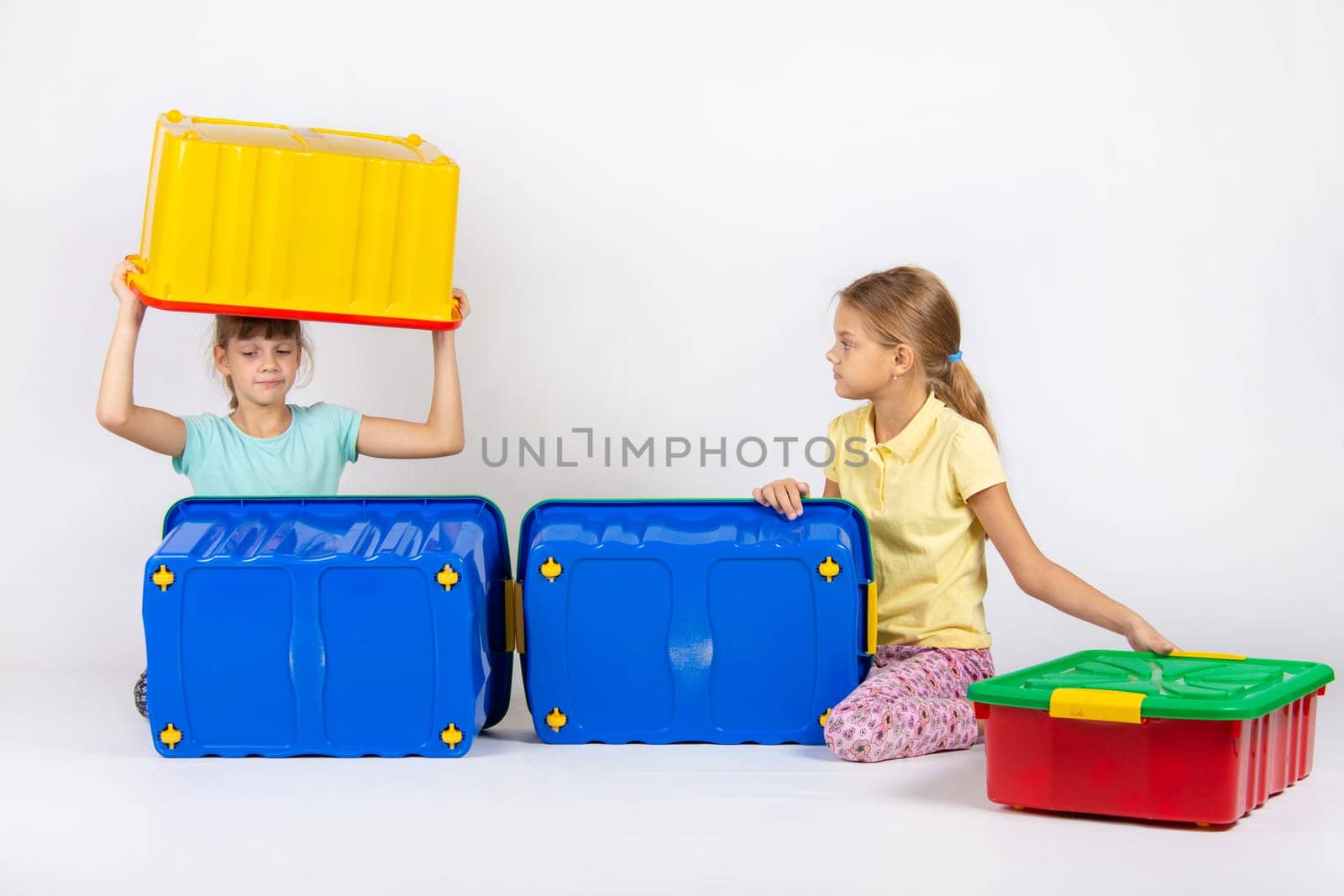 Two girls play with large plastic boxes