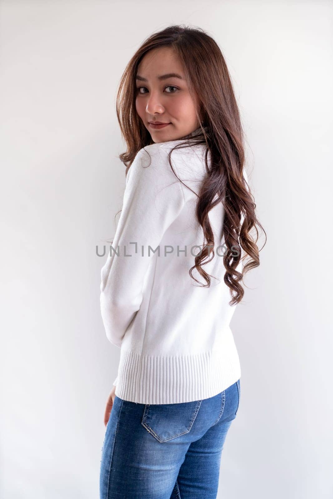 Portrait of good-looking beautiful young asian adult girl wearing white sweater for winter pointing to blank copy space on white background