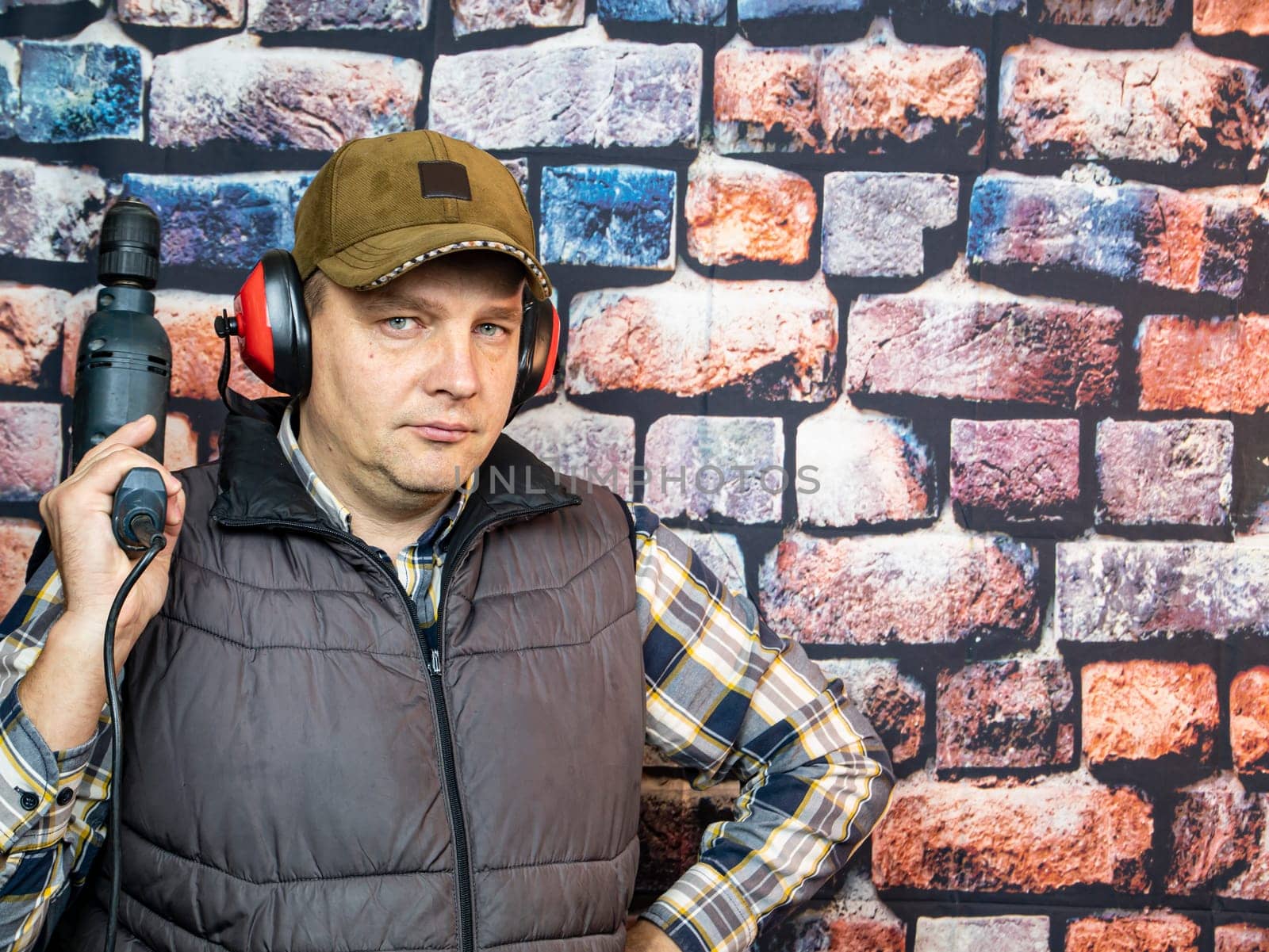 A man with a drill on the background of the wall. Working. Profession.