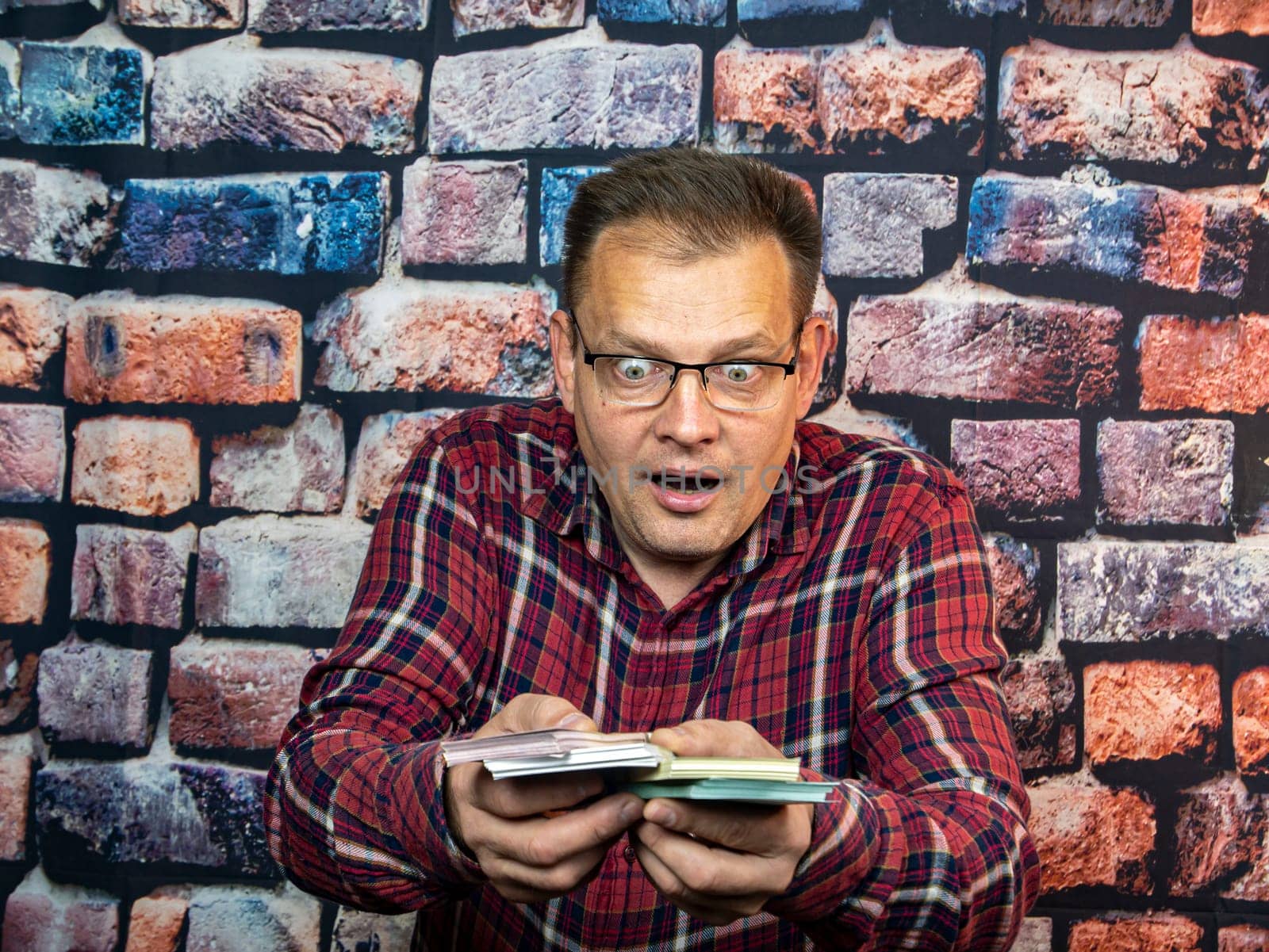 A man with glasses is surprised at the money in his hands. Delight. The salary.