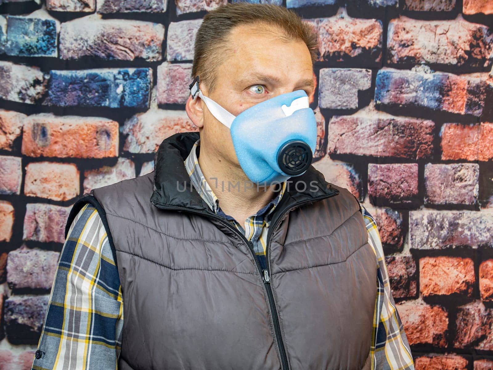 A man in a respirator against the background of the wall. Working. Profession.