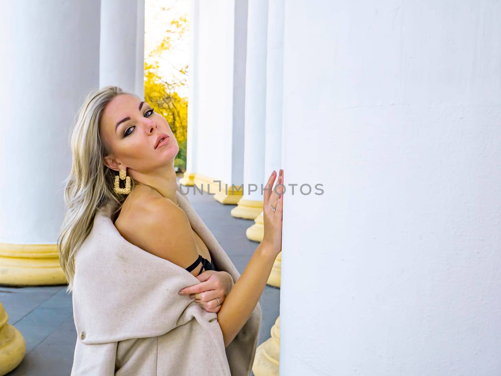 Blonde girl on a background of white columns of a building. Model photo. Women.