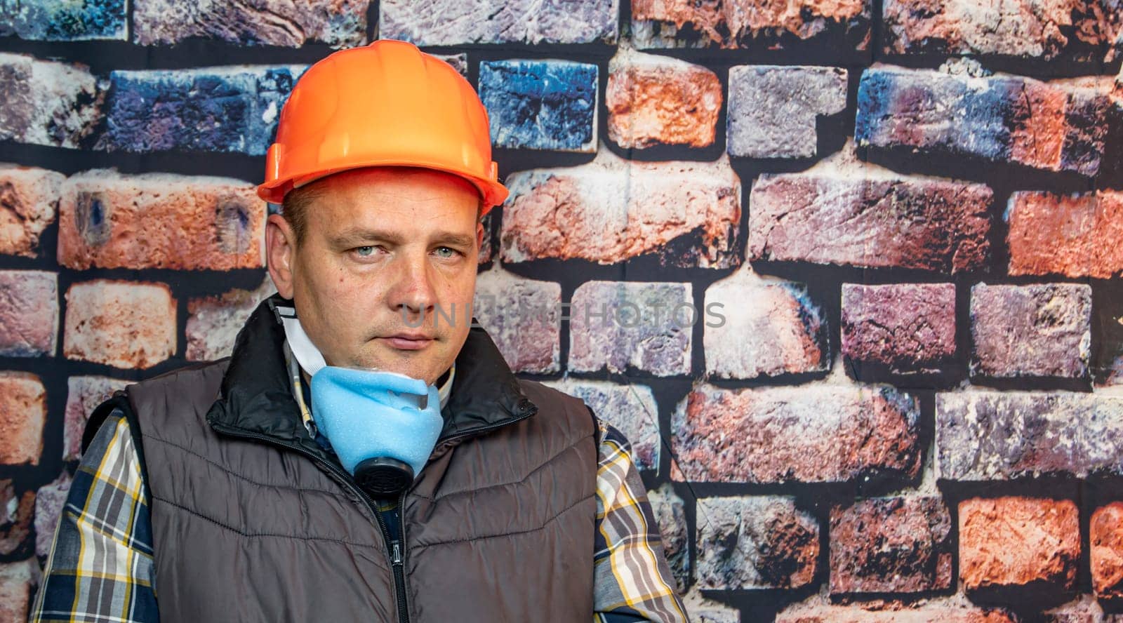A man in a respirator against the background of the wall. Working. Profession.