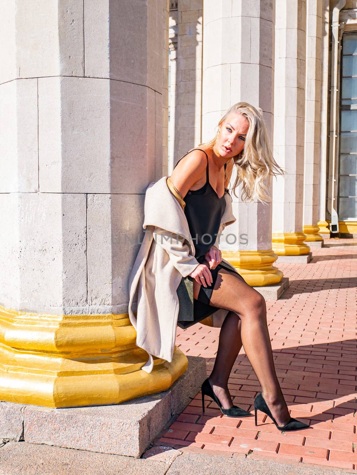 Blonde girl on a background of white columns of a building. Model photo. Women.