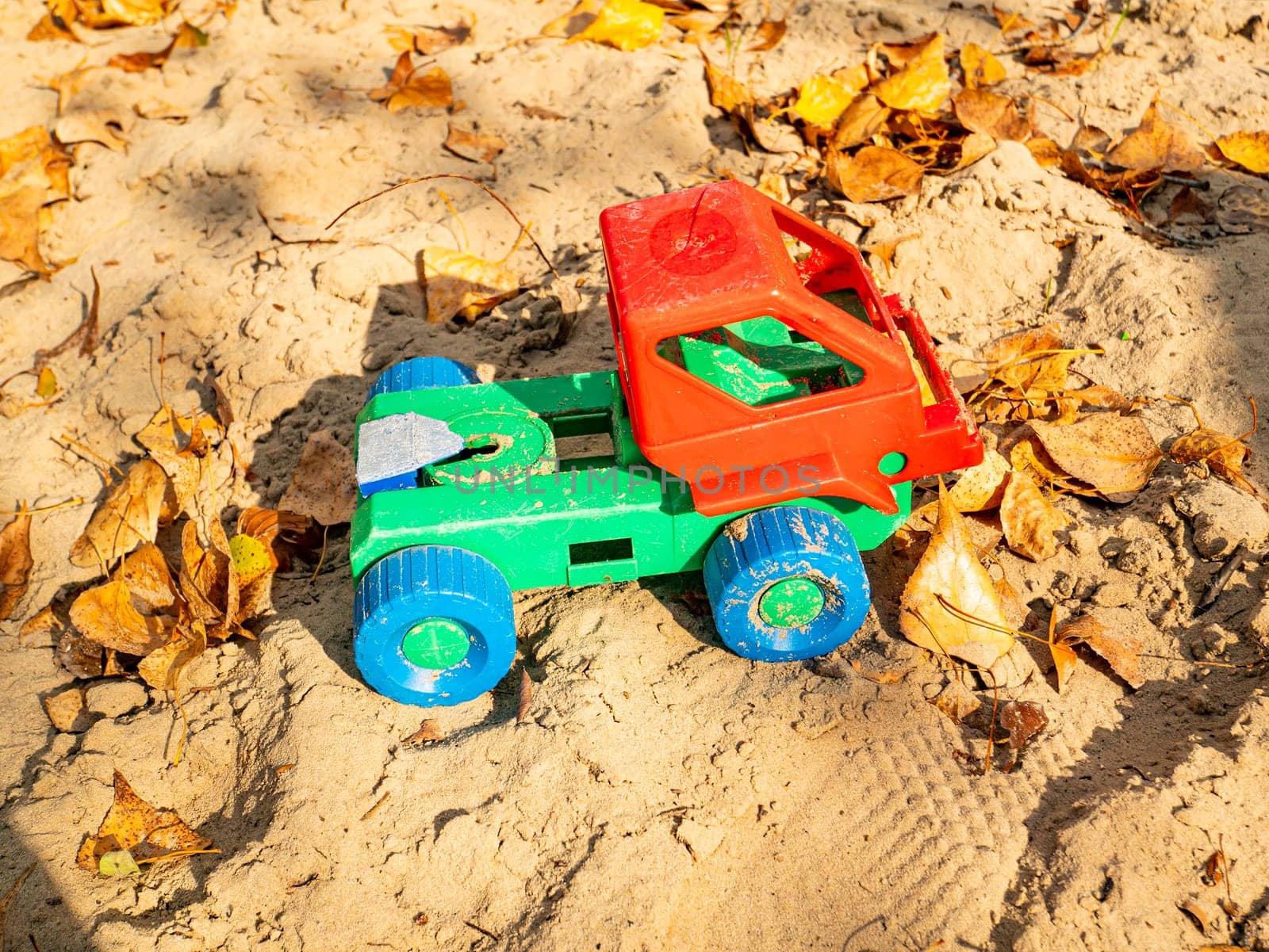 Children's plastic toy lorry in the sand. Children's games.