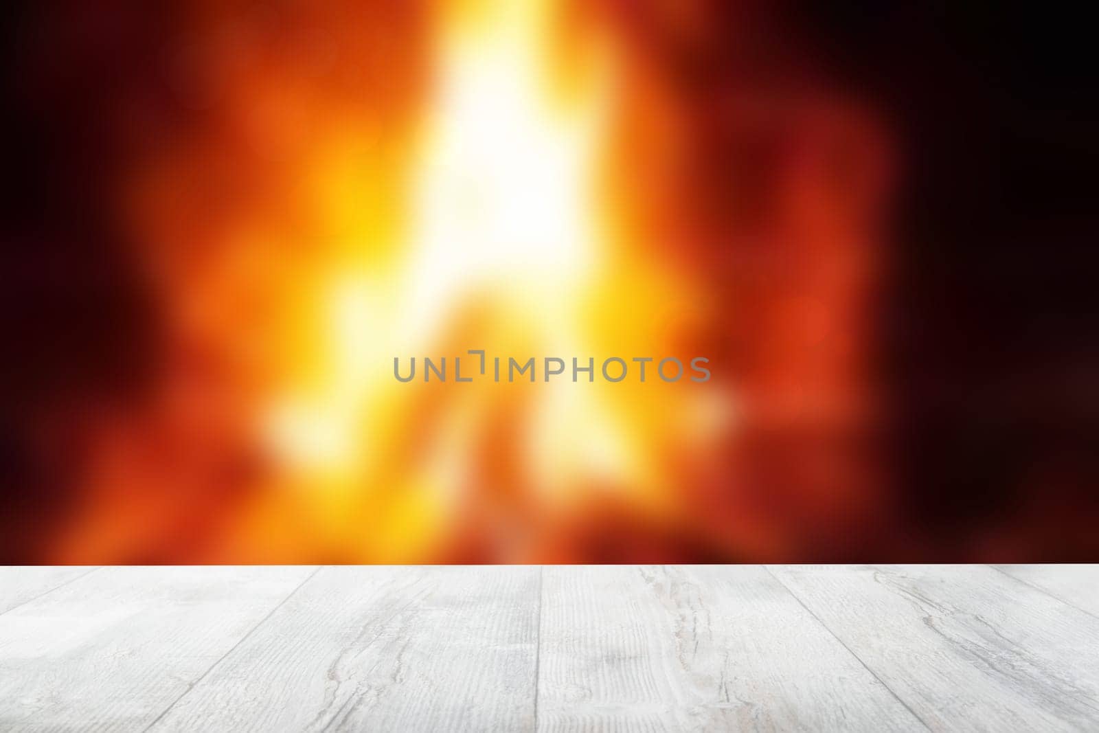 Empty wooden deck table over abstract blurred fireplace with blazing flames at night. Template for your product display montage. Beautiful Christmas backdrop.