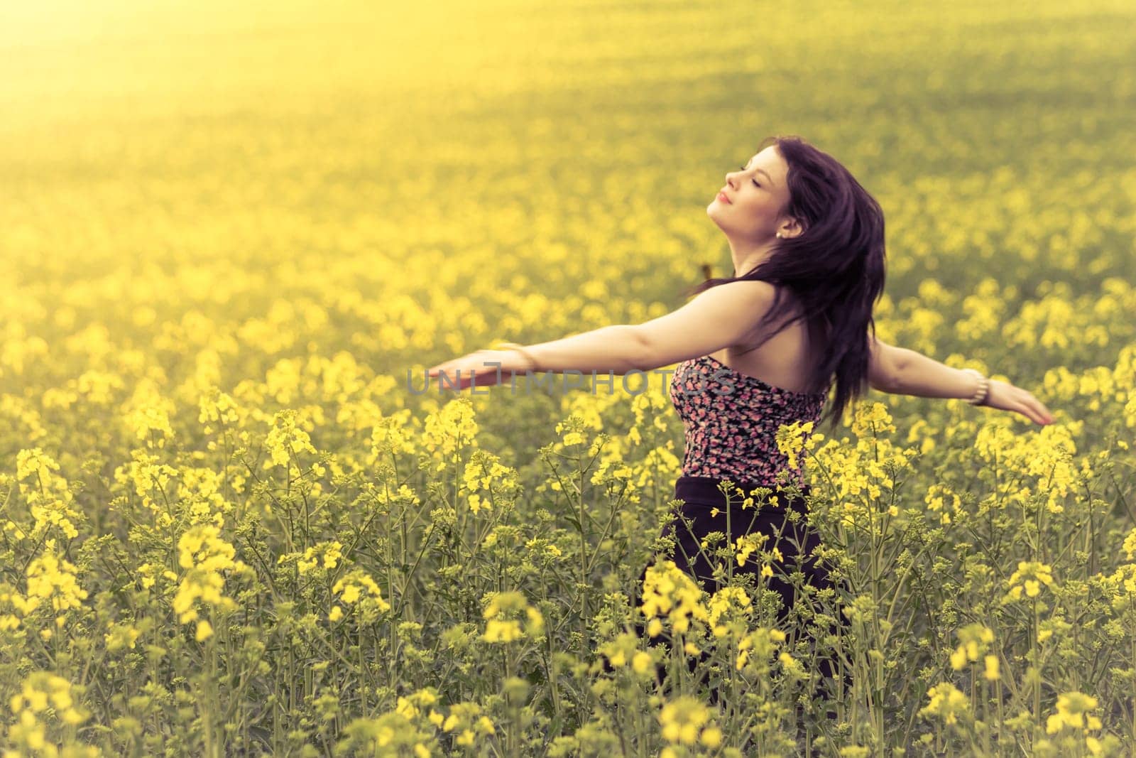 Attractive authentic young girl enjoying the luxury of warm summer sun sunshine and wellbeing youth in wide landscape. Part of series.