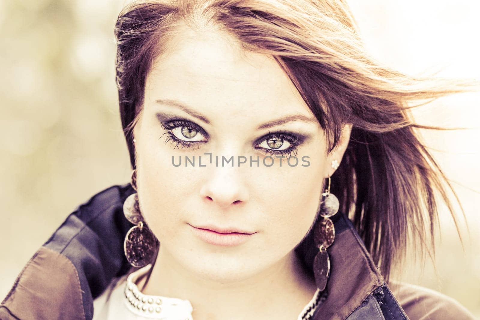 Beauty girl with make-up bright skin look is sexy attractive and serious. Eye shadow earrings and brunette hair in wind. Perfect youth
