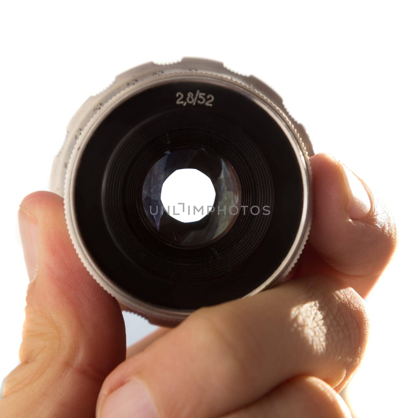 Hand holding retro camera lens on white background