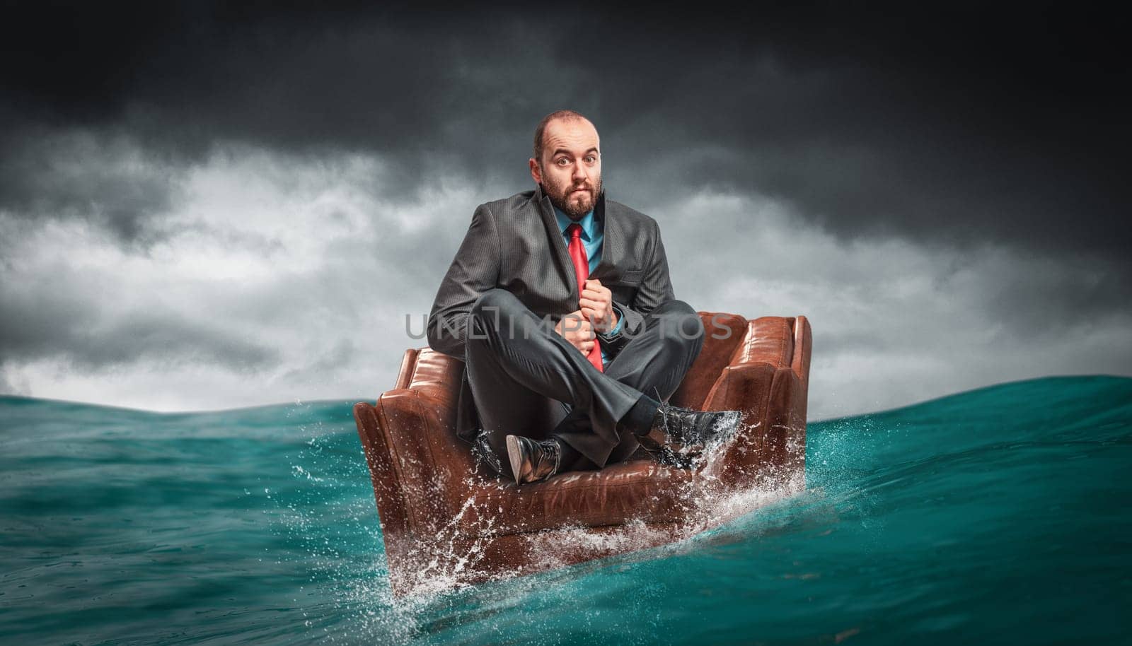 man sitting on an armchair floating on the water of the ocean. concept of crises and problems at work.