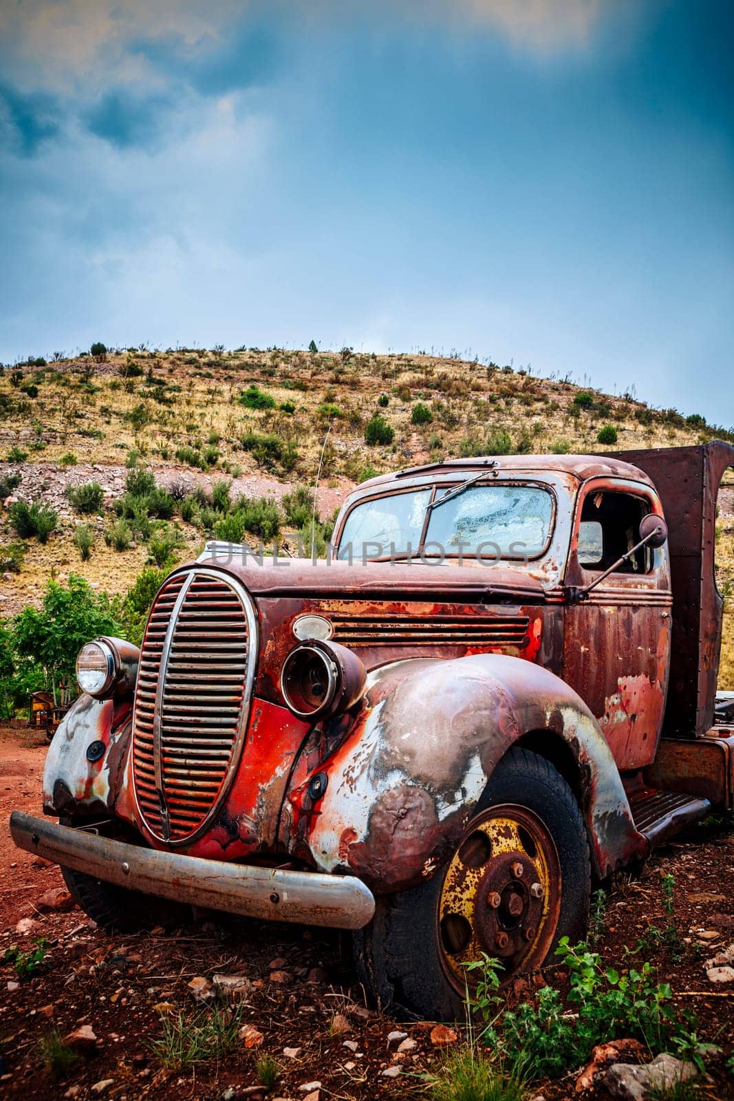 Large rusty old pickup truck rotting out in a field.