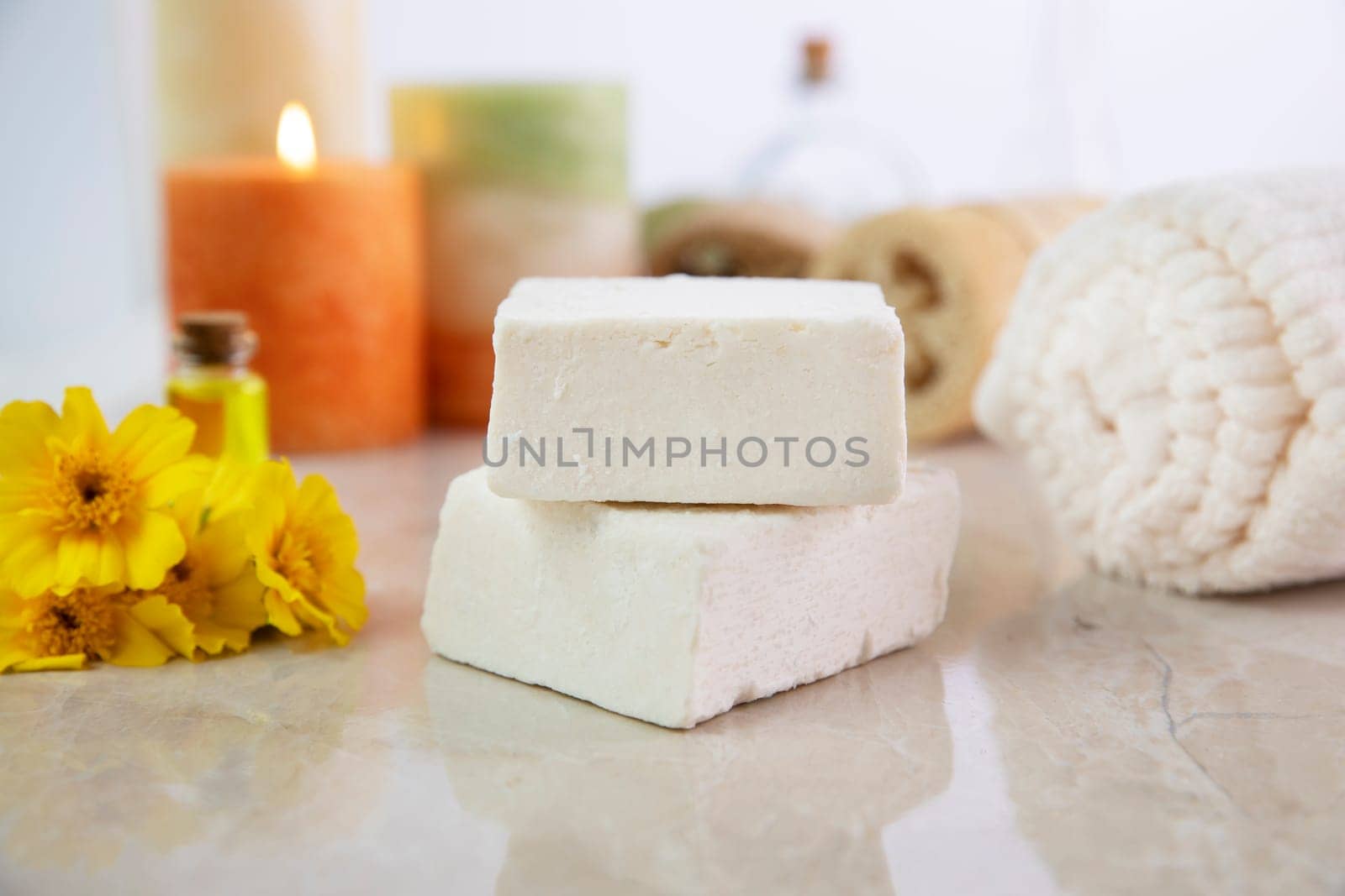 Fresh flower essence soap with towel and candles in the background