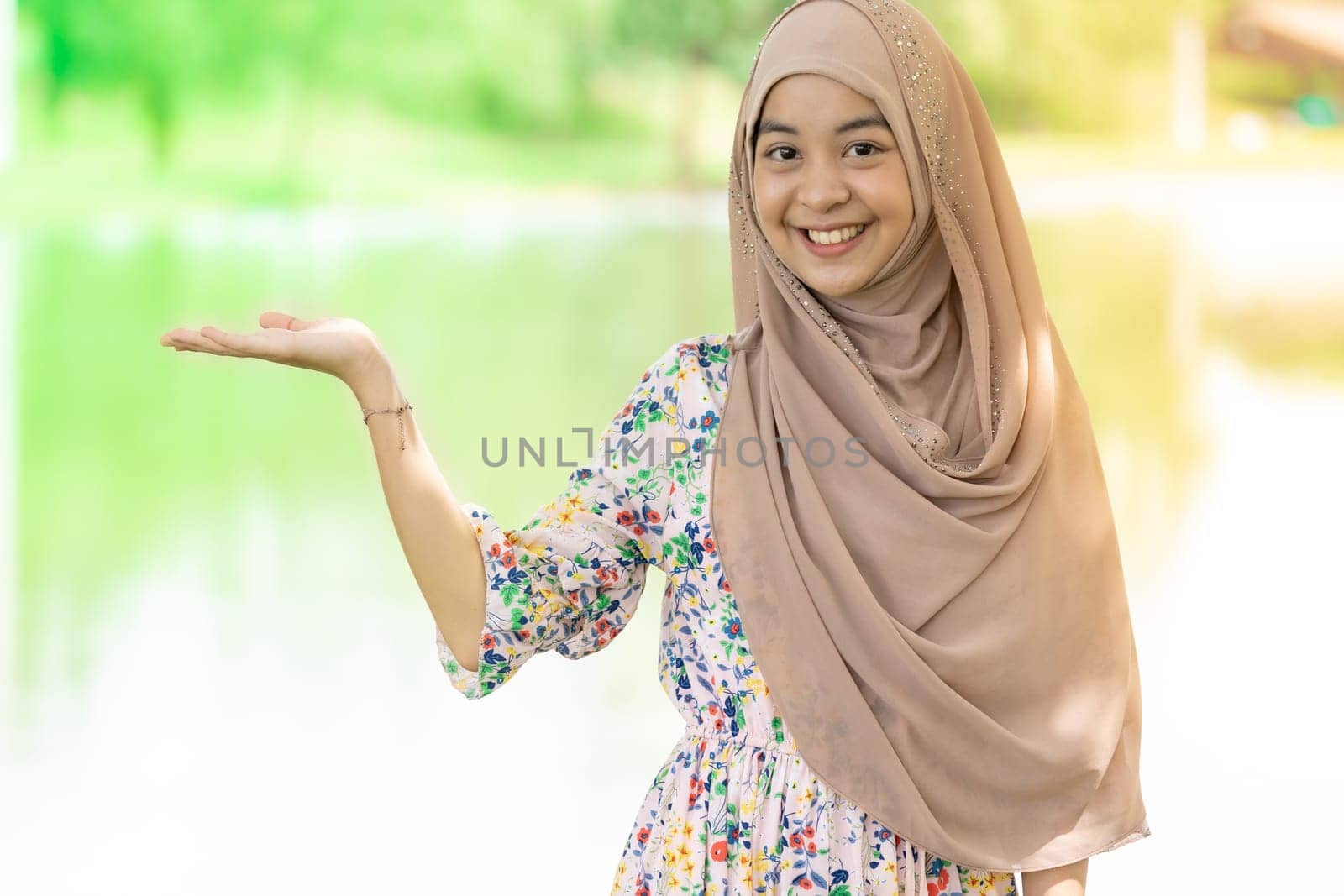 Portrait of good-looking Happy young teenager Muslim islamic asian university girl with hand up on copyspace