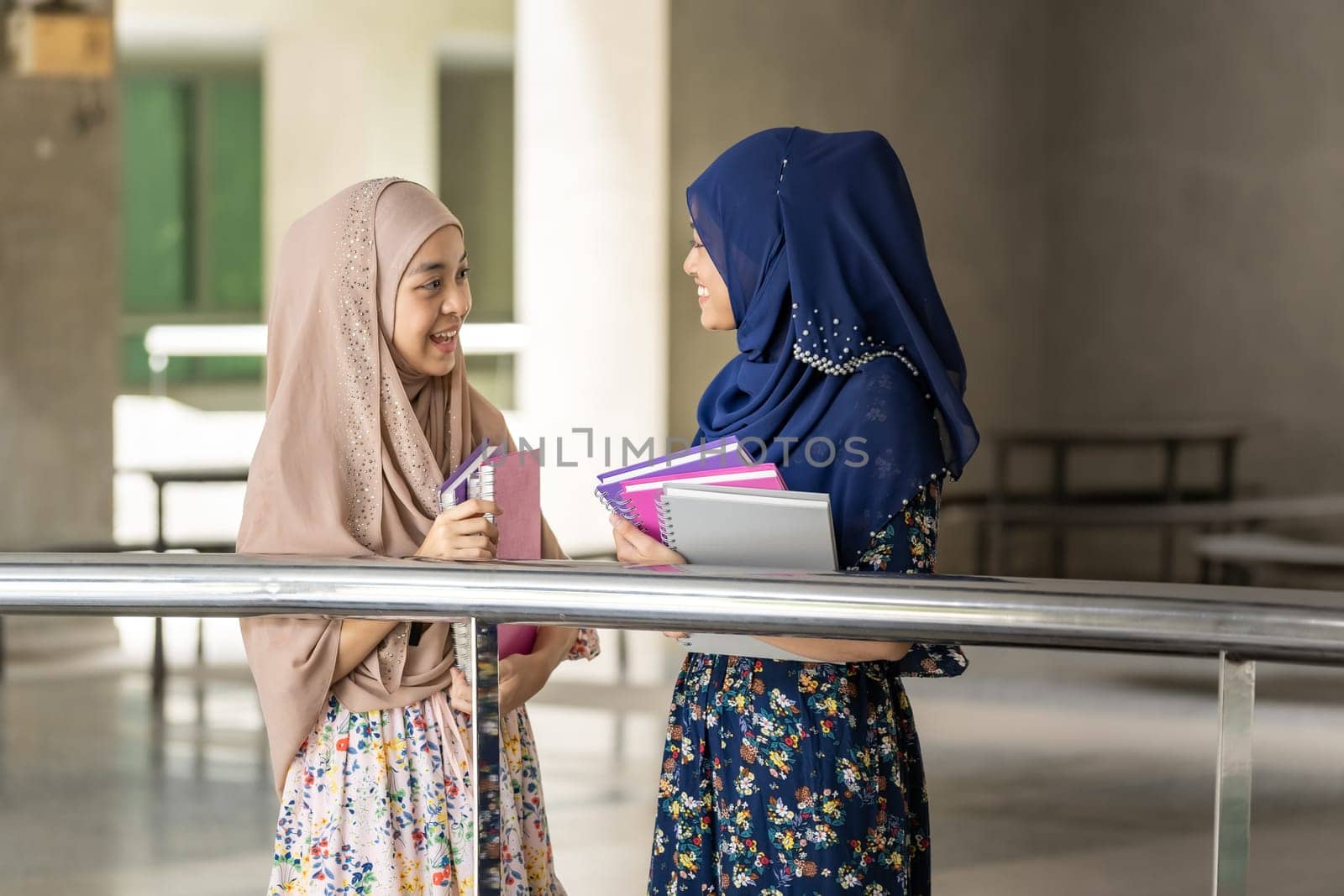 Teenager Young Adult Asian Thai Muslim university college student hold books and talking together outside thier classroom. Using for education background concept
