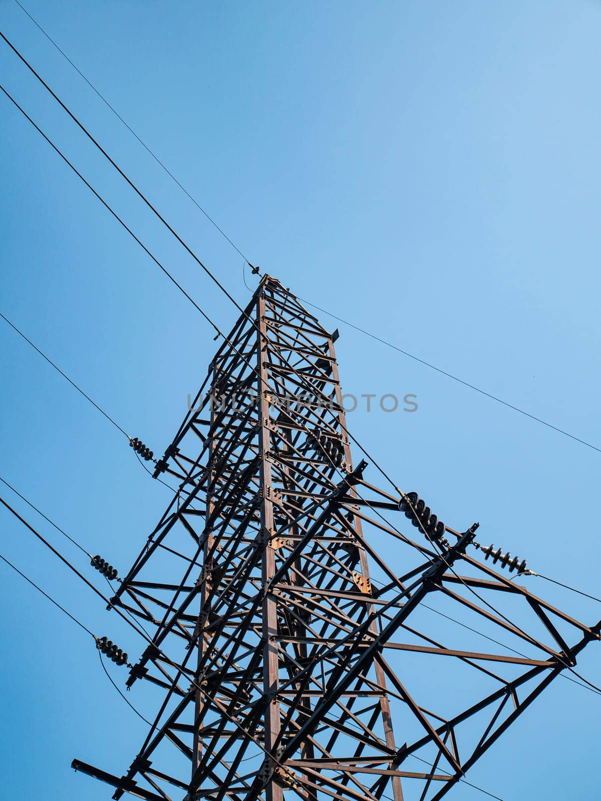 High voltage power line against the blue sky. Industrial landscape. Place for text.