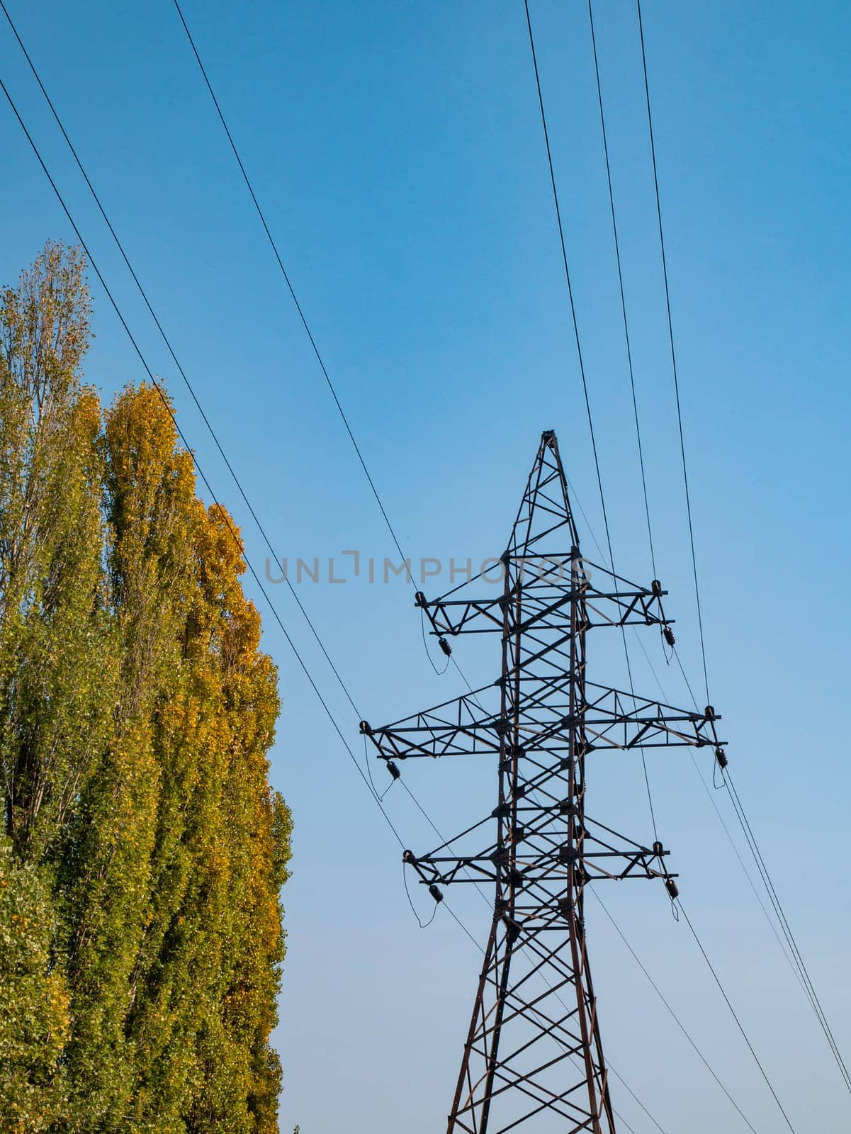 High voltage power line against the blue sky. Industrial landscape. Place for text.