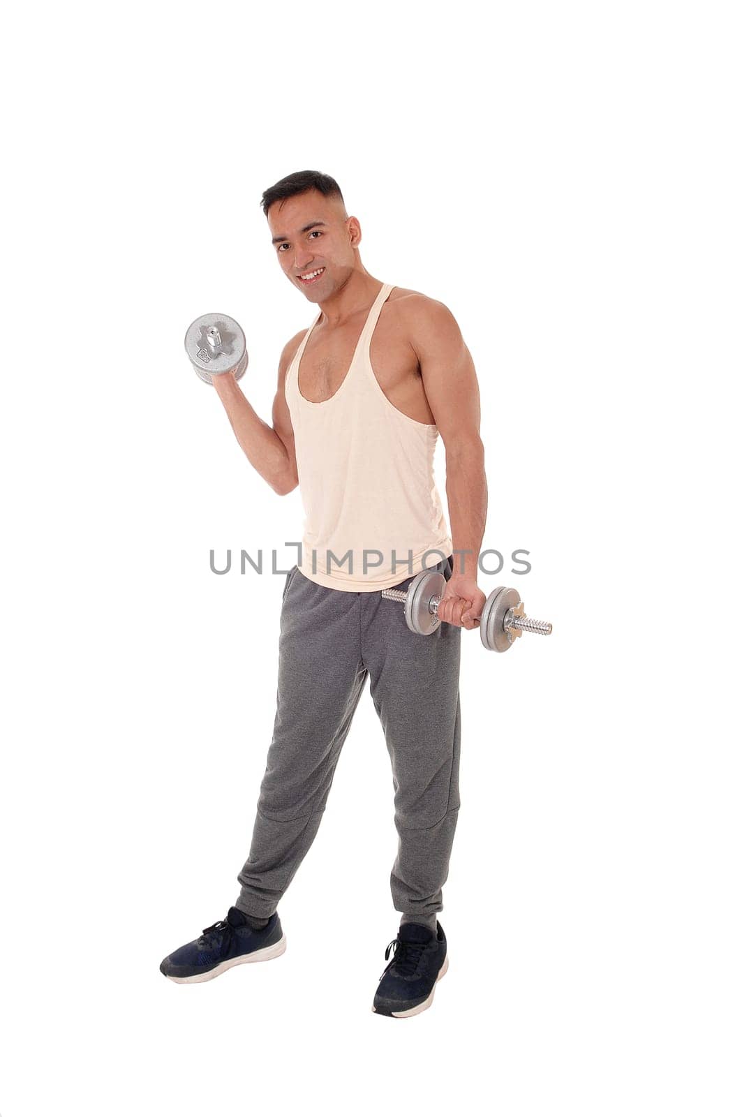 A handsome east Indian man standing in track pants working with.two dumbbells, isolated for white background.