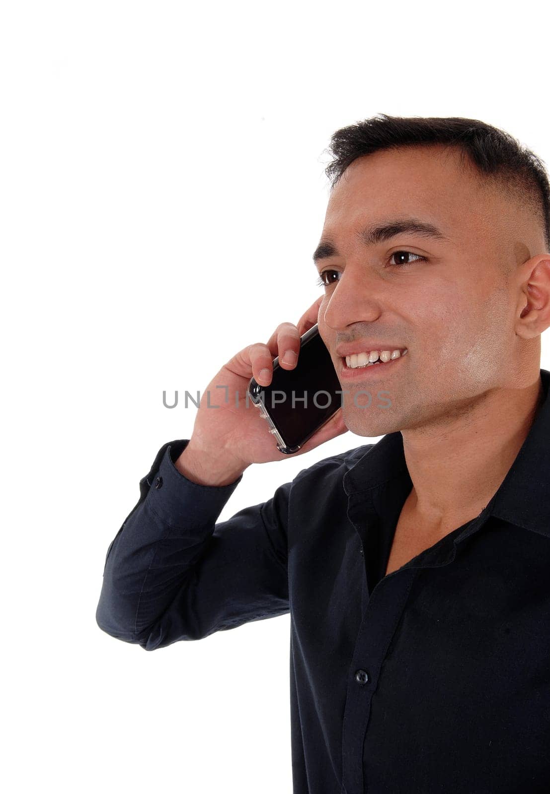 A smiling happy young man in a black shirt standing in the studio.with his phone on his ear and talking, isolated for white background.