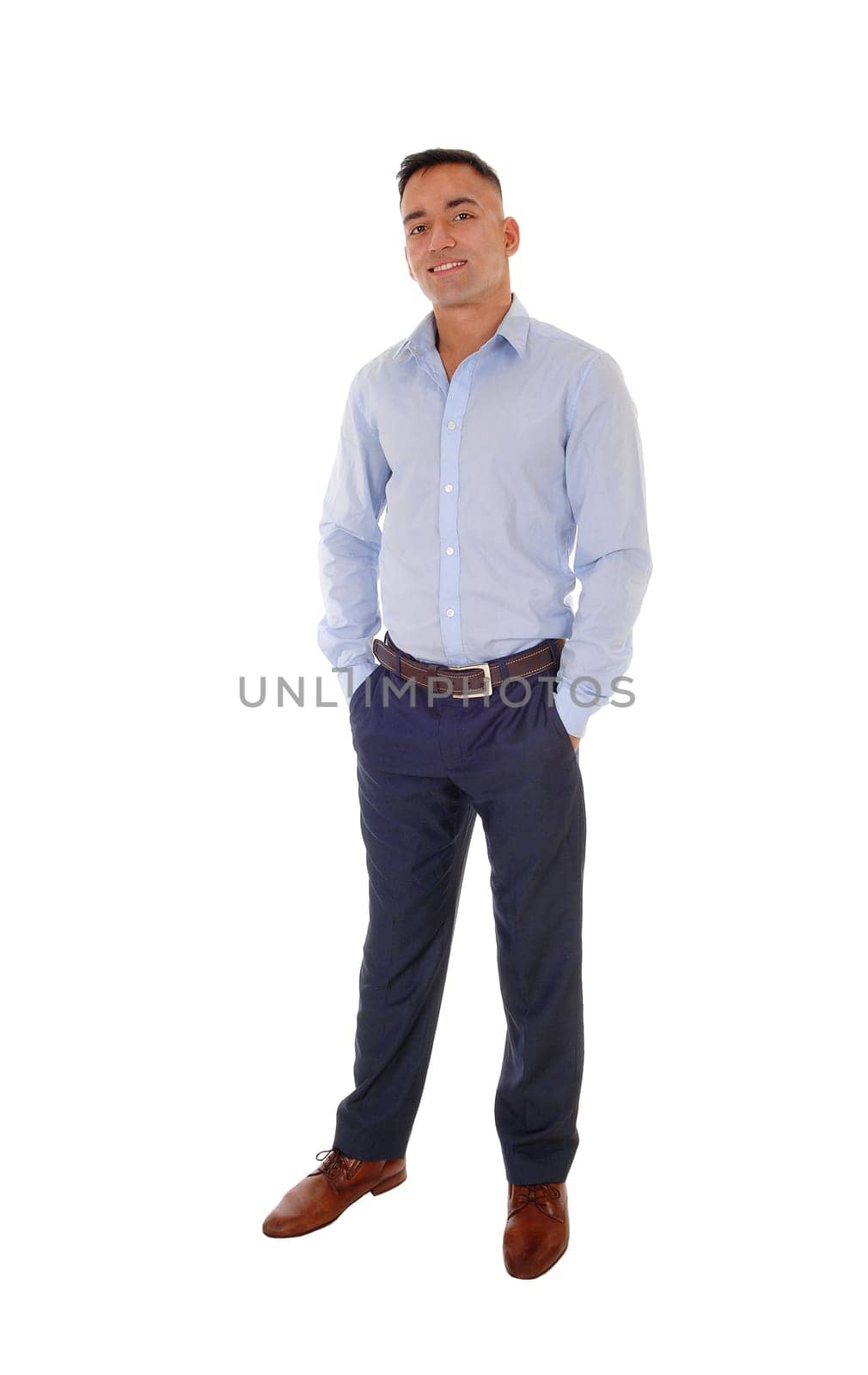 A handsome east Indian man standing in dress pants and a blue shirt.relaxed in the studio, smiling, isolated for white background.