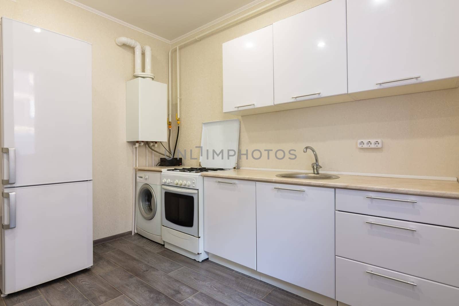 Fragment of the interior of a small kitchen with a fridge and a kitchen set