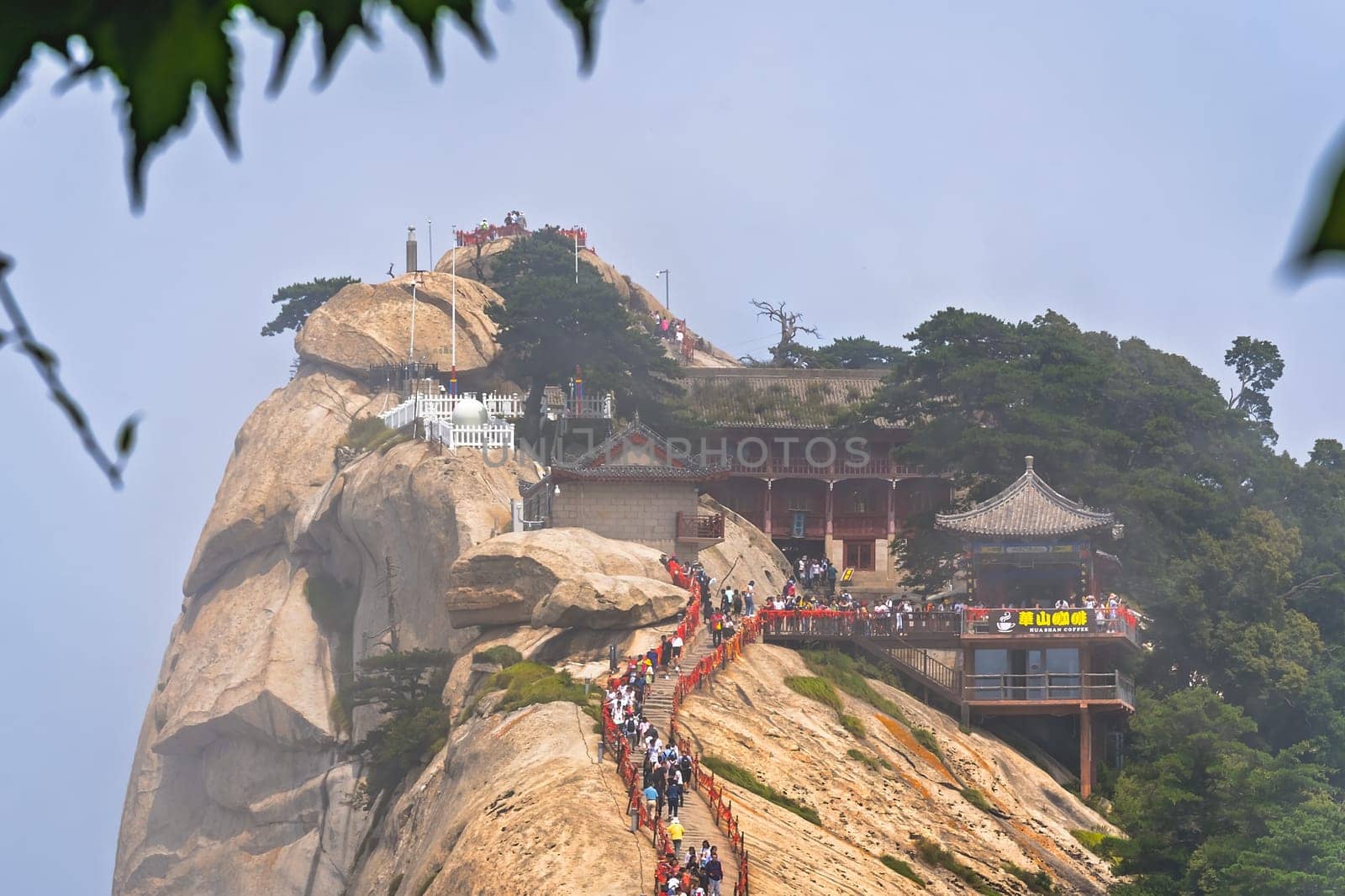 Huashan, China -  August 2019 : Crowds of tourists walking on a narrow ridge on a mountain trail to the West Peak on Huashan mountain, Xian, Shaanxi Province