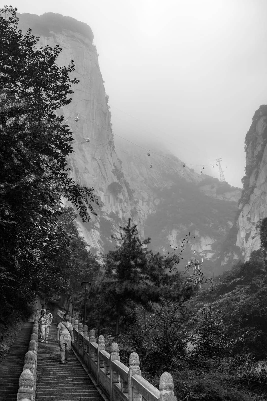 Huashan, China -  August 2019 : Tourists descending the stairs on a steep mountain trail to the North and West Peak on Huashan mountain, Xian, Shaanxi Province