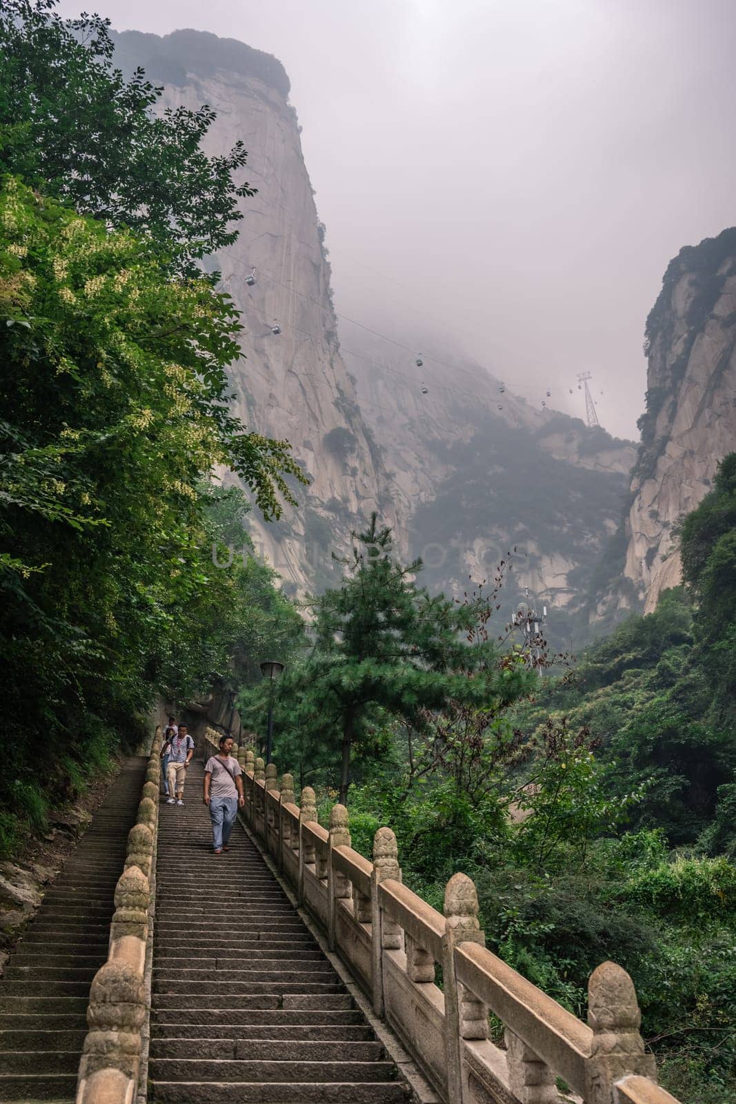 Huashan, China -  August 2019 : Tourists descending the stairs on a steep mountain trail to the North and West Peak on Huashan mountain, Xian, Shaanxi Province