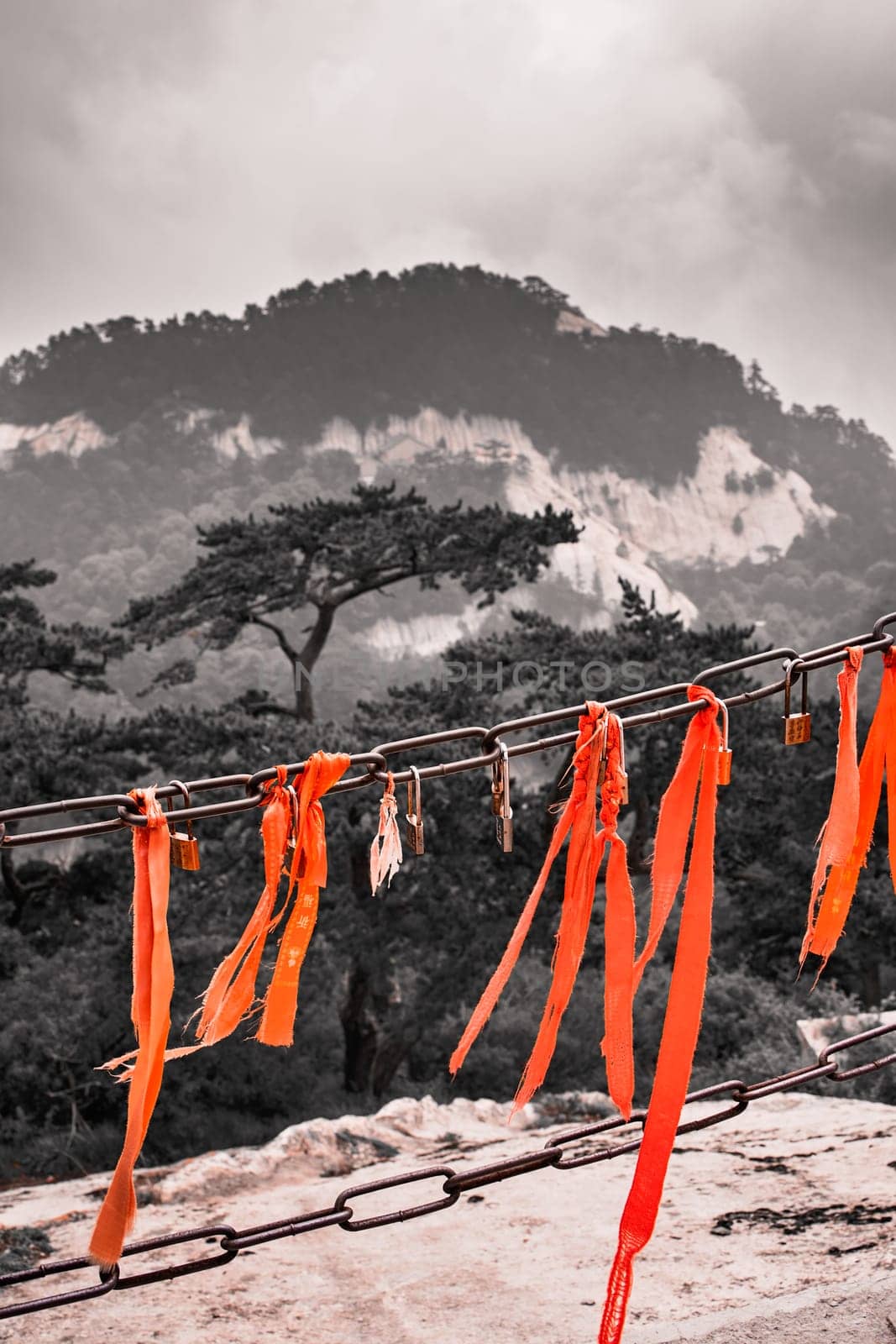 Huashan, China -  August 2019 : Red ribbons attached to the protective barrier on a lookout with the stunning mountain landscape view from the summit of West Peak, Huashan mountain, Shaanxi Province