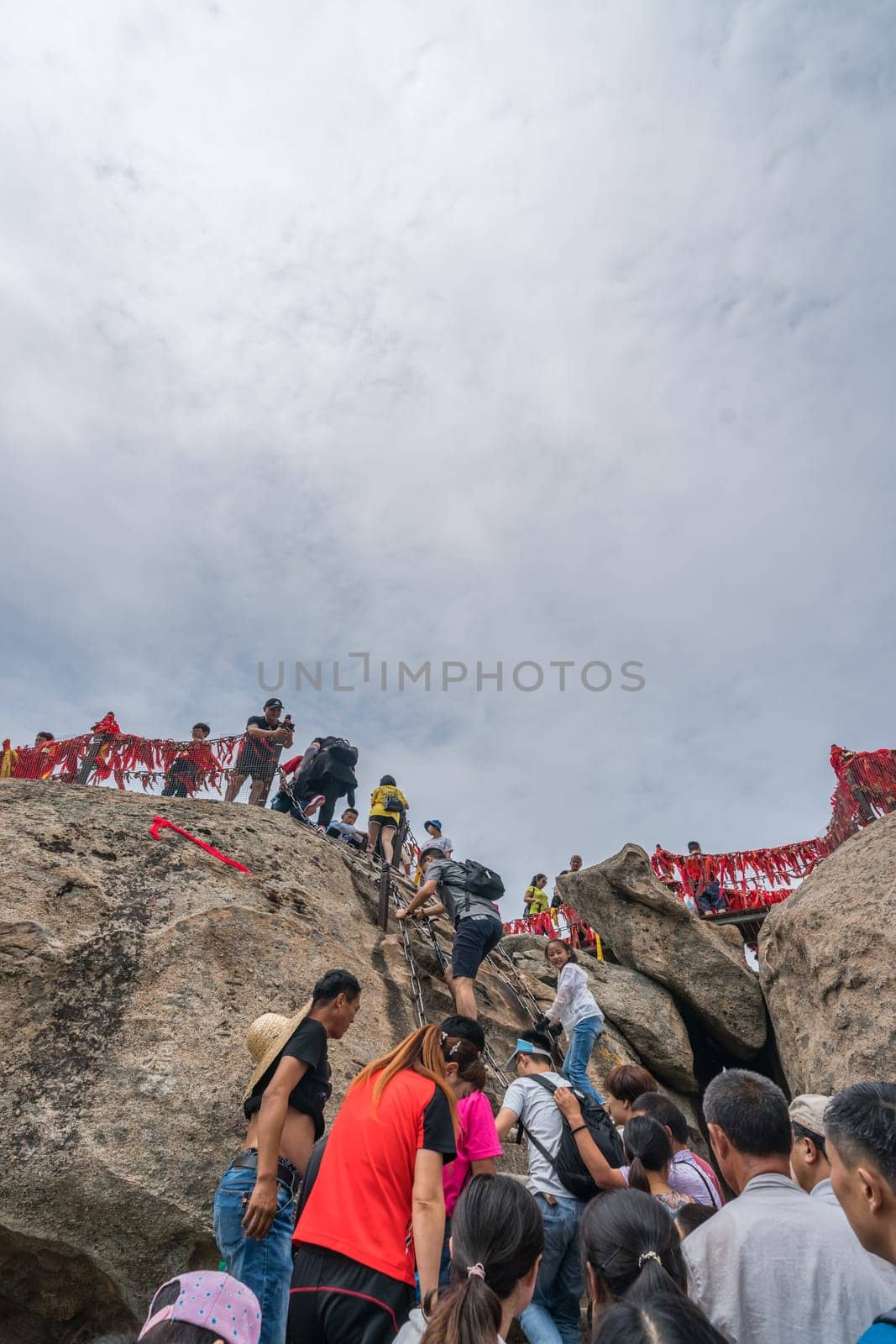 Huashan, China -  August 2019 : Crowds of tourists walking on a mountain trail to the summit of a West Peak on Huashan mountain, Xian, Shaanxi Province
