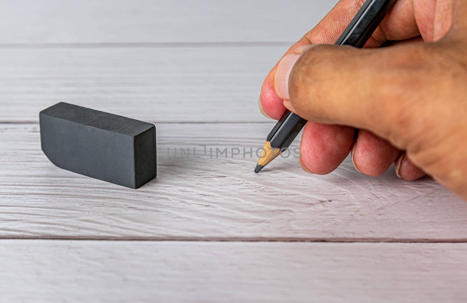 Hand human with black pencil on blurred white table background