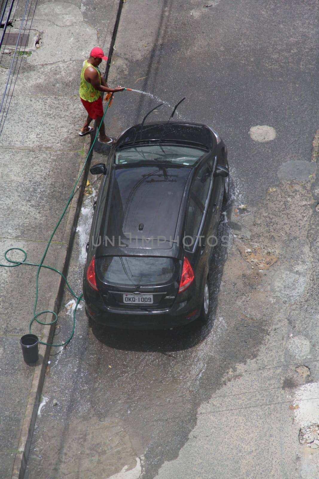 SALVADOR, BAHIA / BRAZIL - December 3, 2014: Man washes car with hose in Cabula neighborhood in Salvador (BA), featuring a waste of drinking water. (Joa Souza / Panthermedia).