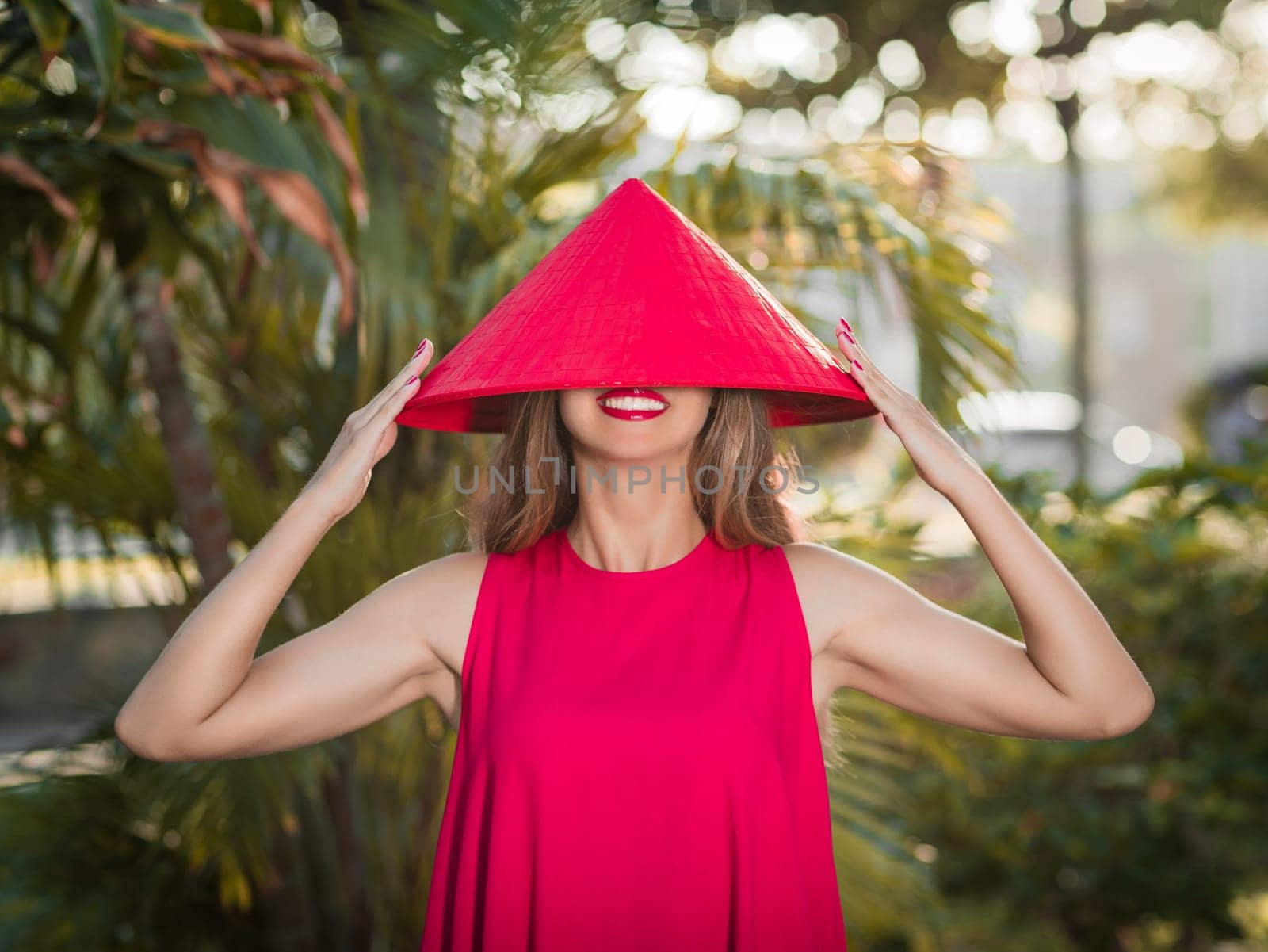 Fashion portrait of a beautiful woman in red conical hat outdoor
