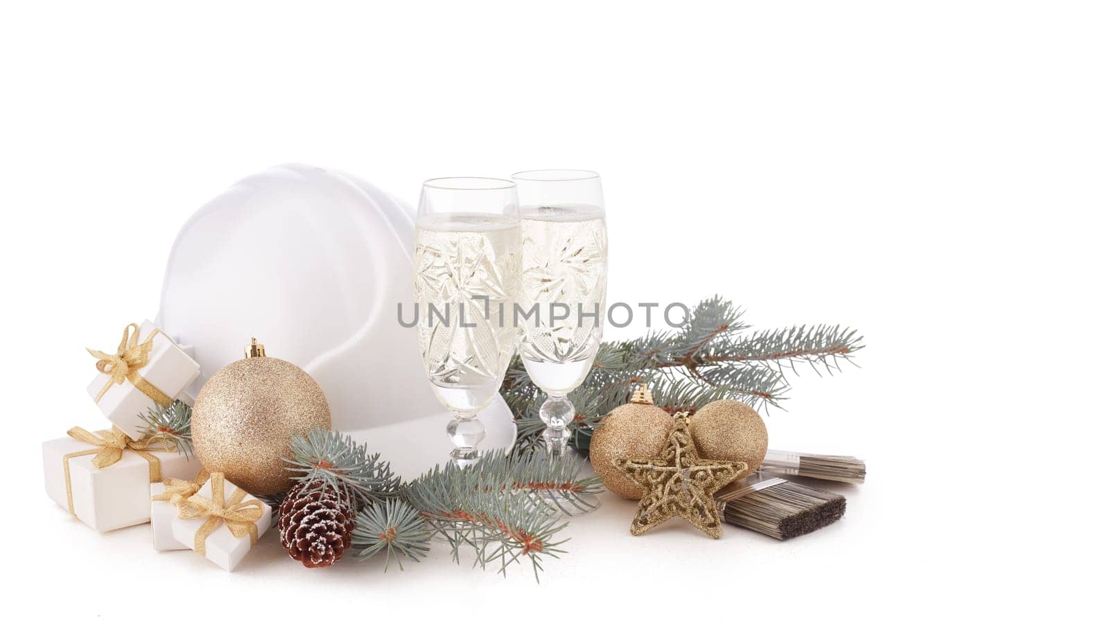 Construction hard hat, fir tree branches, two glasses with champagne, gift boxes and Christmas ornament isolated on a white background. New Year and Christmas construction background