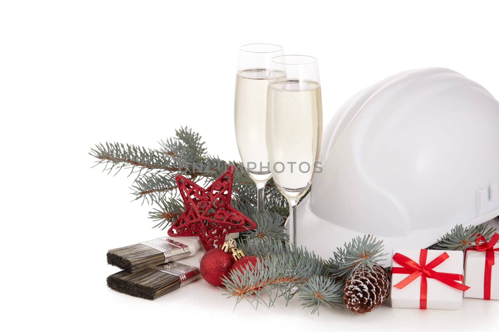 Construction hard hat, fir tree branches, two glasses with champagne, gift boxes and Christmas ornament isolated on a white background. New Year and Christmas construction background