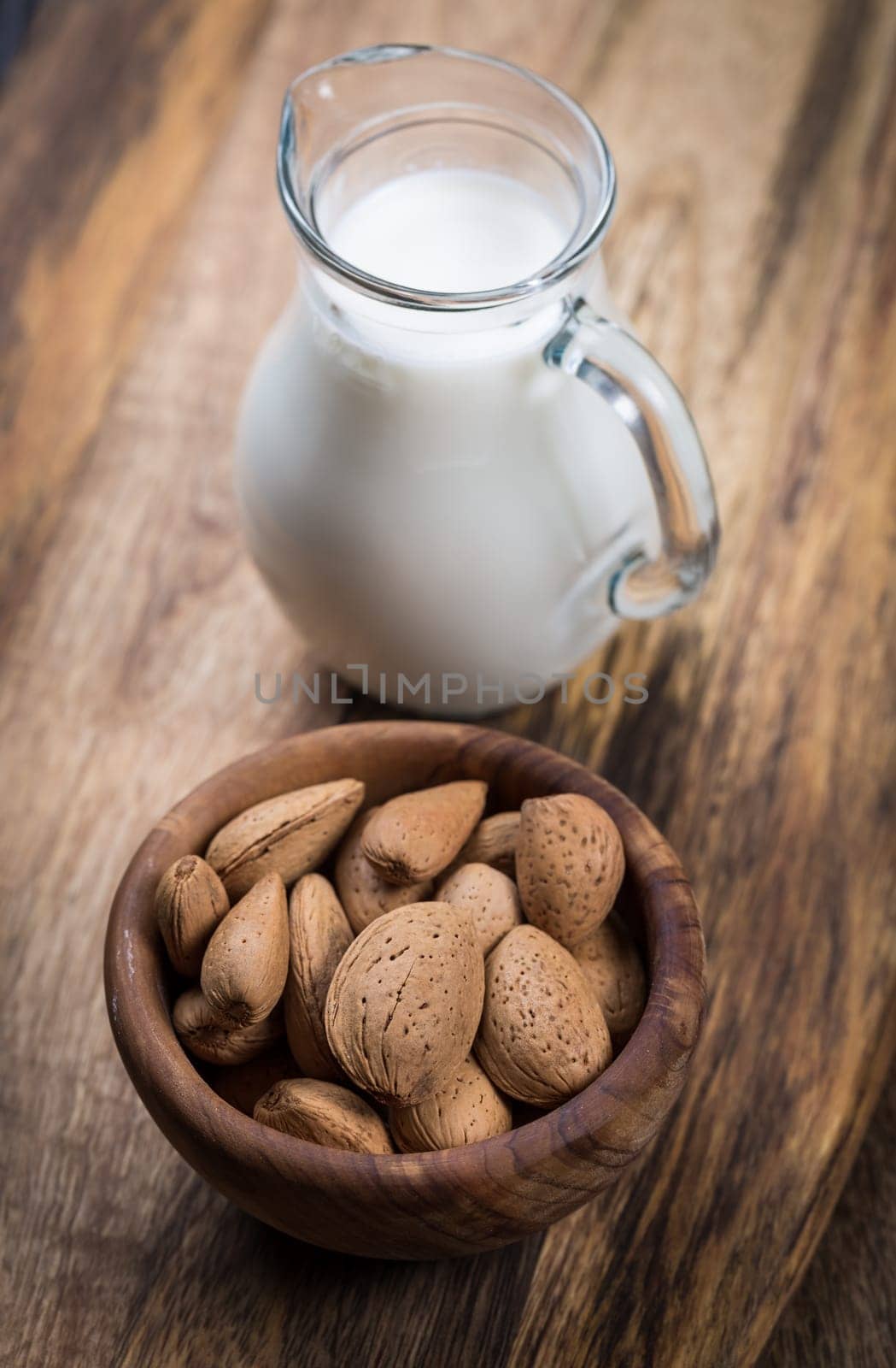 Jar of almond milk with almond nuts on wooden background