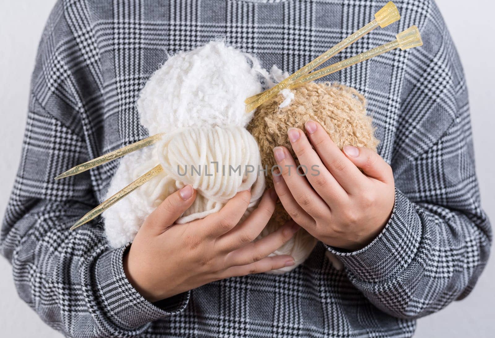 Detail of hands holding white wool for knitting