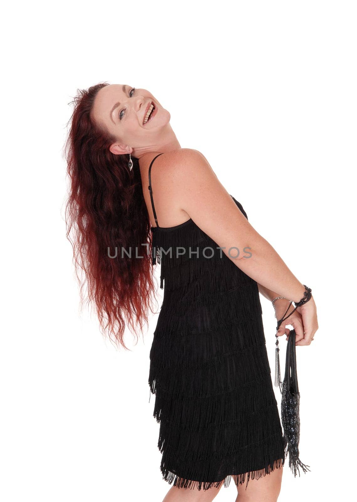 A beautiful woman standing in a black dress in profile with her long.red hair falling in the back, isolated for white background.