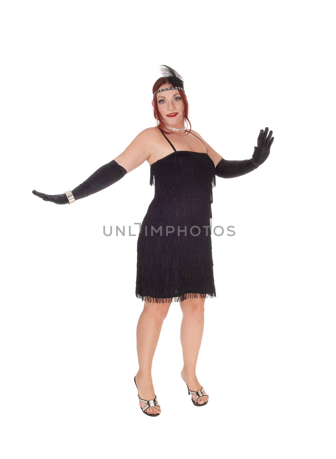 A gorgeous woman in a black dress of the 20 century and long cloves.standing in the studio, isolated for white background.