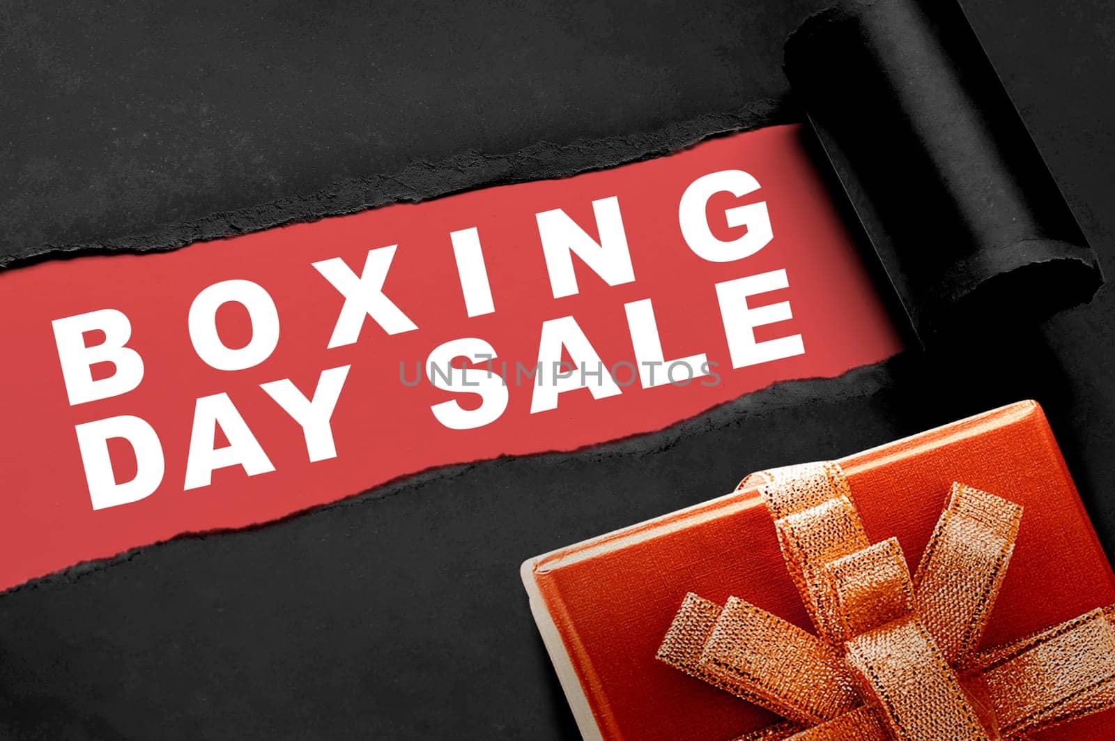 Gift box with a ripped paper showing Boxing Day Sale text on a red background