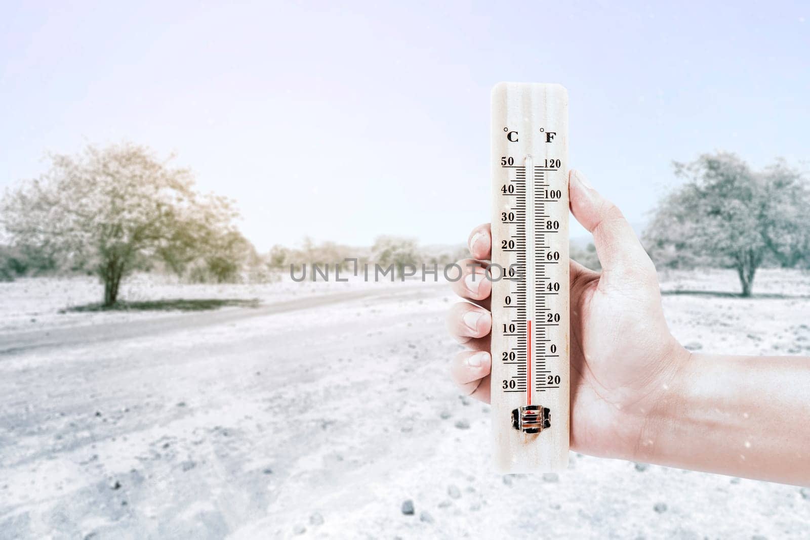 Hand holding thermometer measuring the temperature outdoor with a clear sky background. Heatwave concept